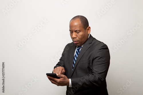 African American Business Man Uses Smart Phone on Light Gray Background