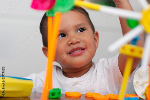 Fotografi A cute boy playing with preschool math manipulative toys and with a facial expression that shows wonder or thinking