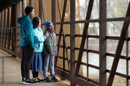 Hispanic Woman And Sons Look Out Over River From Bridge