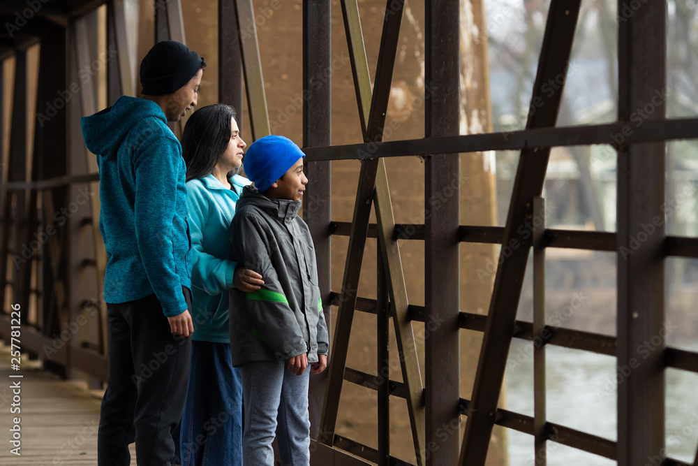 Hispanic Woman And Sons Look Out Over River From Bridge Hispanic Woman And Sons Look Out Over River From Bridge