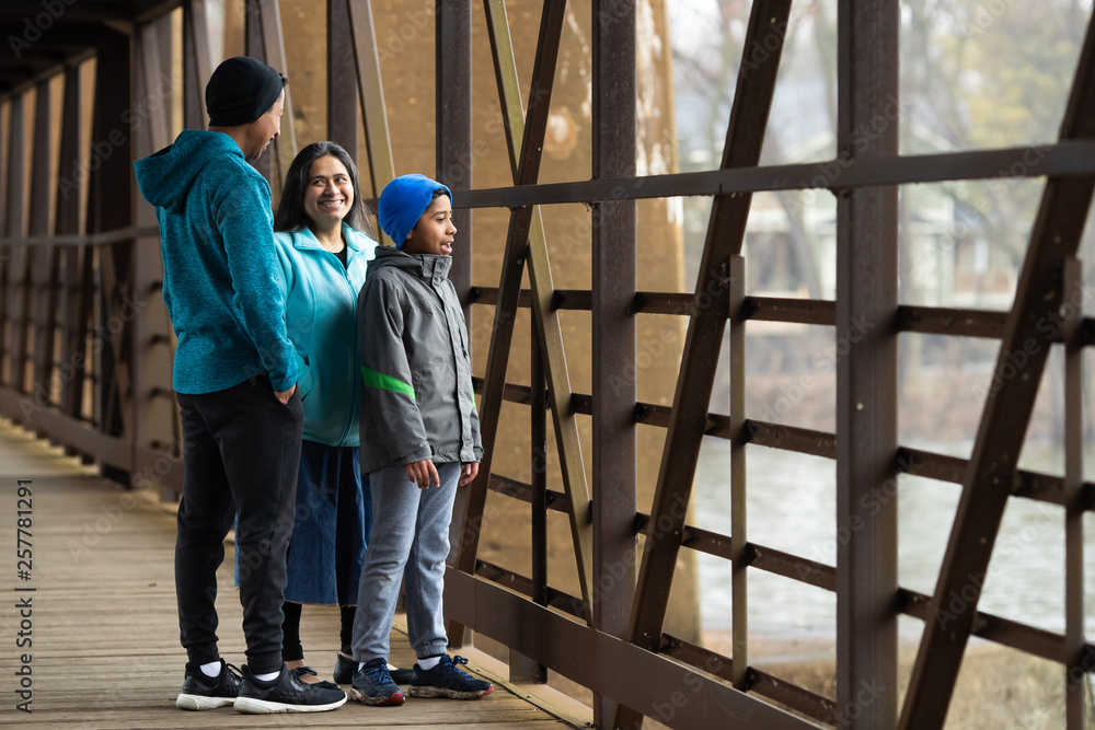 Fototapeta premium Hispanic Woman And Sons Look Out Over River From Bridge