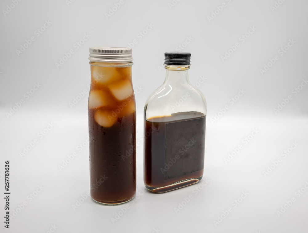 Cold Brew Coffee in glass bottle with black cap and cube ice in cylinder glass bottle isolated on white Cold Brew Coffee in glass bottle with black cap and cube ice in cylinder glass bottle isolated on white