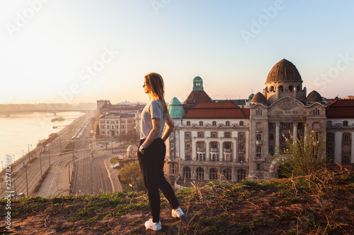 Beautiful woman standing opposite famous facade and entrance to Hotel Gellert on banks of Danube in Budapest, Hungary photo