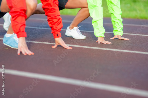 Closeup of Hands Of Two caucasian Athletes Standing Prepared For Running on Track Course.