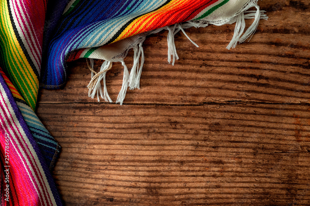 Cinco de mayo fiesta party and indigenous cultures of Mexico concept theme with a Mexican rug called a serape isolated on wood background with copy space