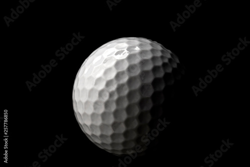 High contrast studio shot of golf ball isolated on black background with dramatic light