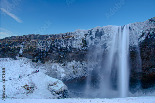 Iceland waterfall seljalandsfoss frozen in winter with blue sky. 