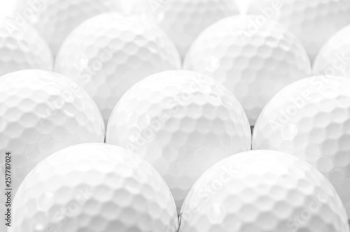 Brightly lit image of several golf balls creating a full frame pattern isolated on white background