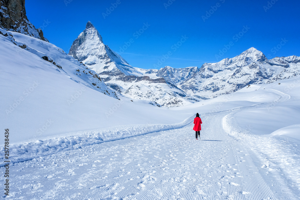 Young woman tourist  walking in the snow to see beautiful Matterhorn Mountain, Zermatt, Switzerland.