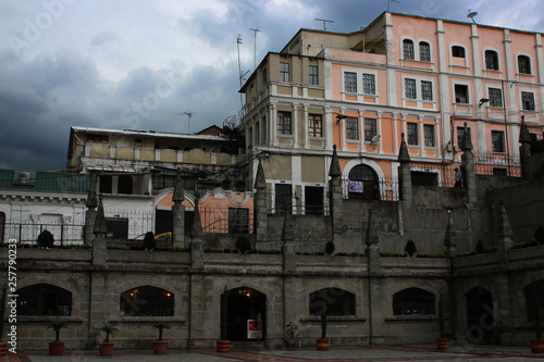 Dark grey and dirty road with colorfoul buildings on the background and a dark sky full of clouds in Quito Ecuador