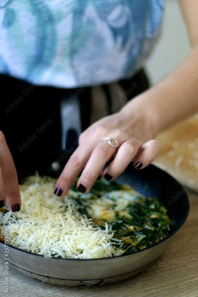 Unrecognizable person making frittata with chicory and cheese. Selective focus.