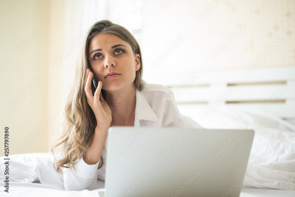 Happy Beautiful woman working on a laptop on the bed in the house Happy Beautiful woman working on a laptop on the bed in the house