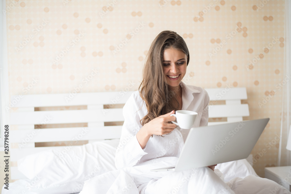 Happy Beautiful woman working on a laptop on the bed in the house Happy Beautiful woman working on a laptop on the bed in the house