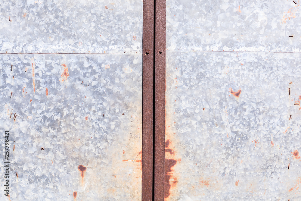 old detailed aged vintage rusty red brown textured zinc alloy metal sheet exterior fence door used in construction industry as warehouse building material. Good for background, backdrop, wallpaper