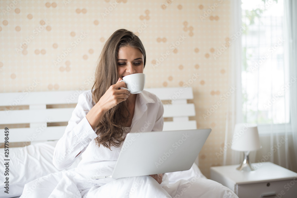 Happy Beautiful woman working on a laptop on the bed in the house Happy Beautiful woman working on a laptop on the bed in the house
