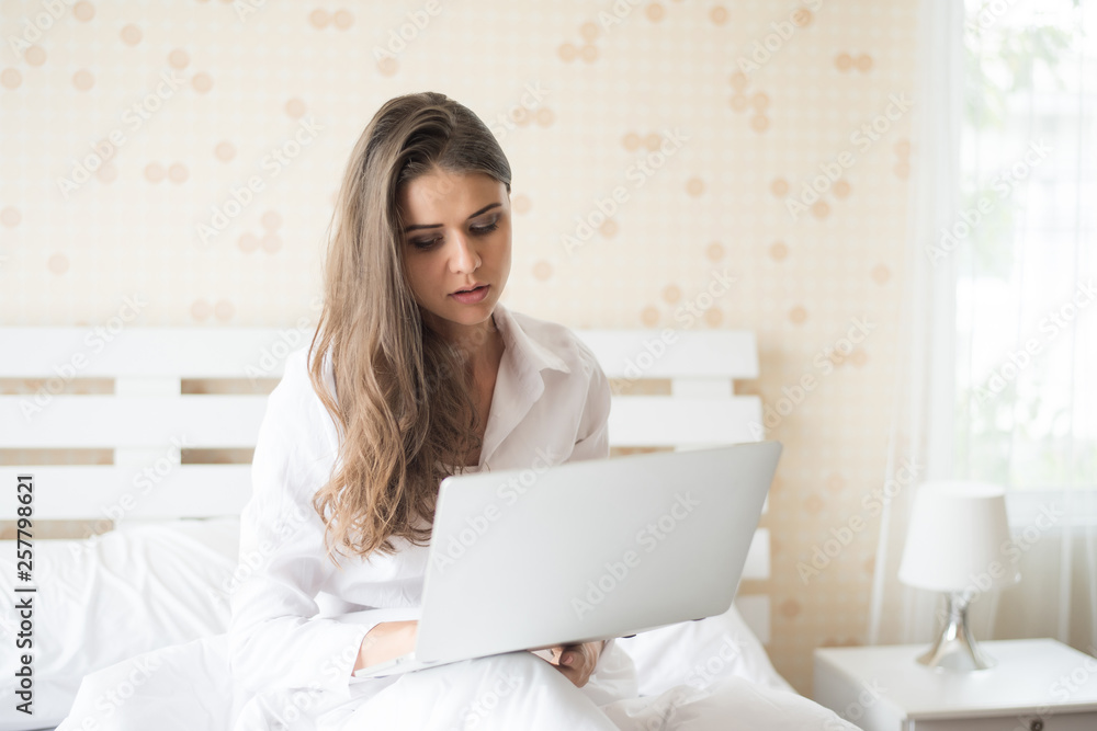 Happy Beautiful woman working on a laptop on the bed in the house Happy Beautiful woman working on a laptop on the bed in the house