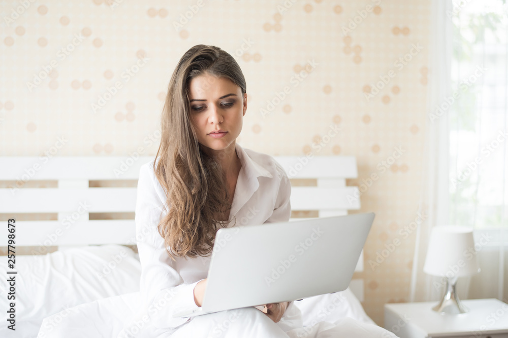 Happy Beautiful woman working on a laptop on the bed in the house Happy Beautiful woman working on a laptop on the bed in the house