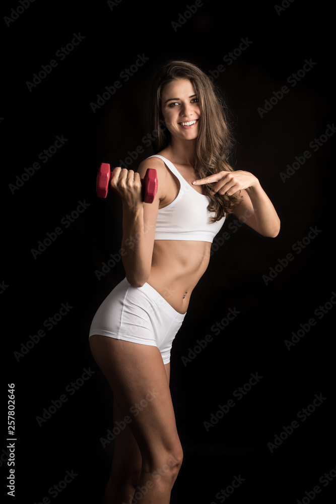 Portrait of young beautiful woman making physical exercises with dumbbells