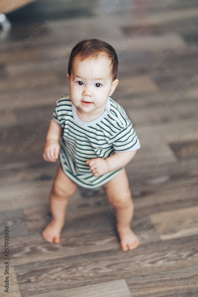 cute toddler boy or girl standing near bed, smiling and looking at camera in apartment cute toddler boy or girl standing near bed, smiling and looking at camera in apartment