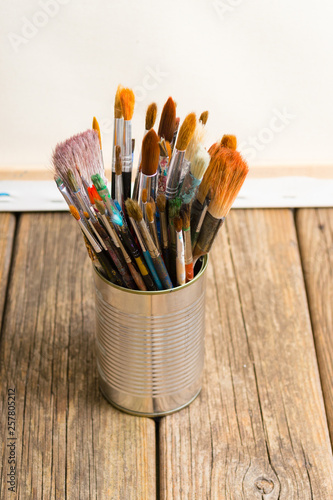 bundle of paintbrush at tin can, artist canvas, rusty wooden
