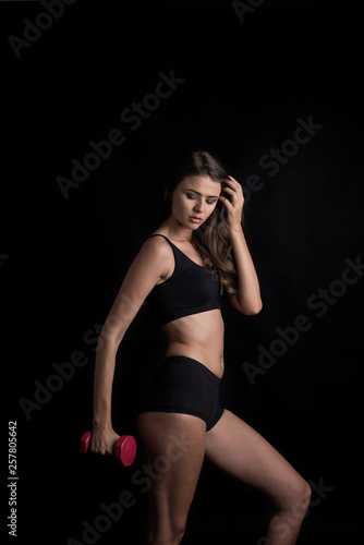 Portrait of young beautiful woman making physical exercises with dumbbells