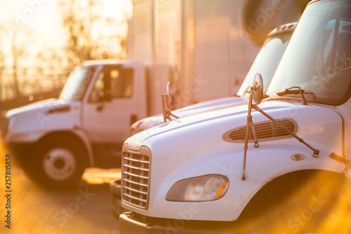 Middle rig semi Trucks standing at the gates of the warehouse for loading lit by the sun