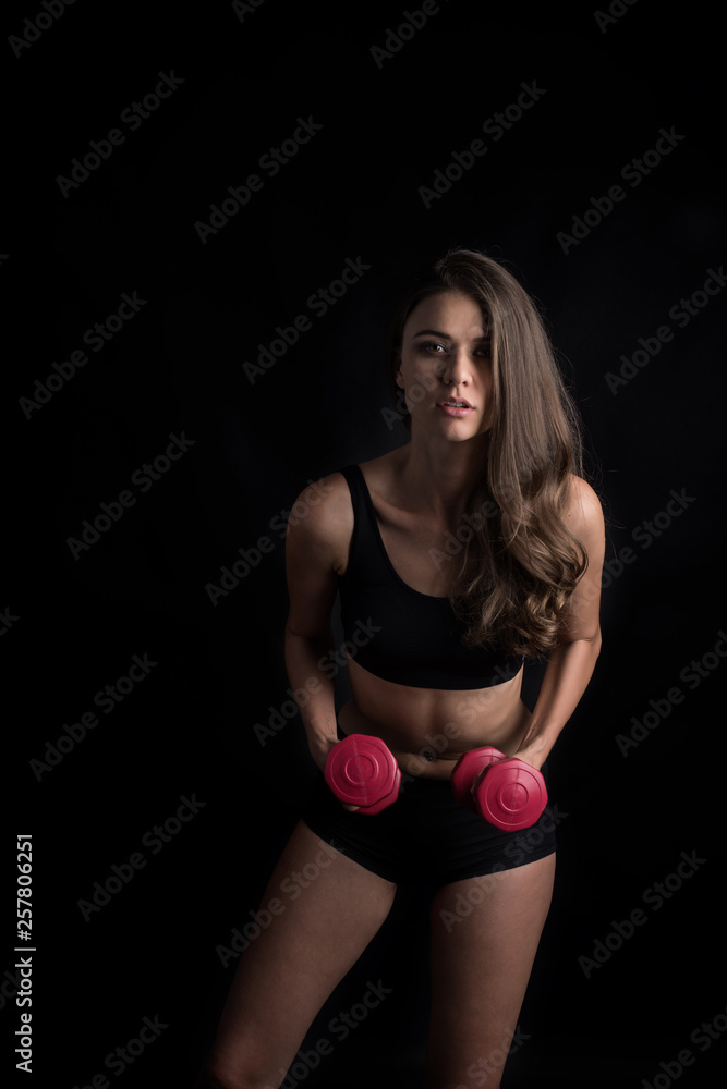 Portrait of young beautiful woman making physical exercises with dumbbells