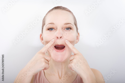 facial gymnastics. the girl does massage and rejuvenating exercises for the face
