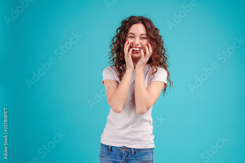 Studio portrait of a brunette genuinely laughing isolated over turquoise background