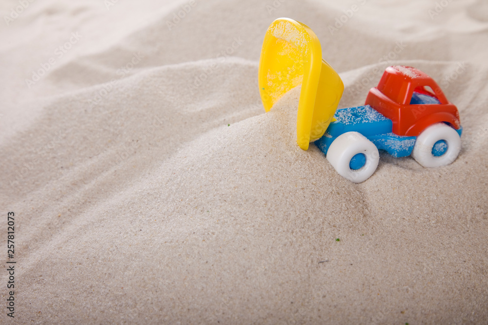 Small dump truck empties sand. Miniature. Children play in the sand. Sand therapy. Psychology and construction. Small dump truck empties sand. Miniature. Children play in the sand. Sand therapy. Psychology and construction.
