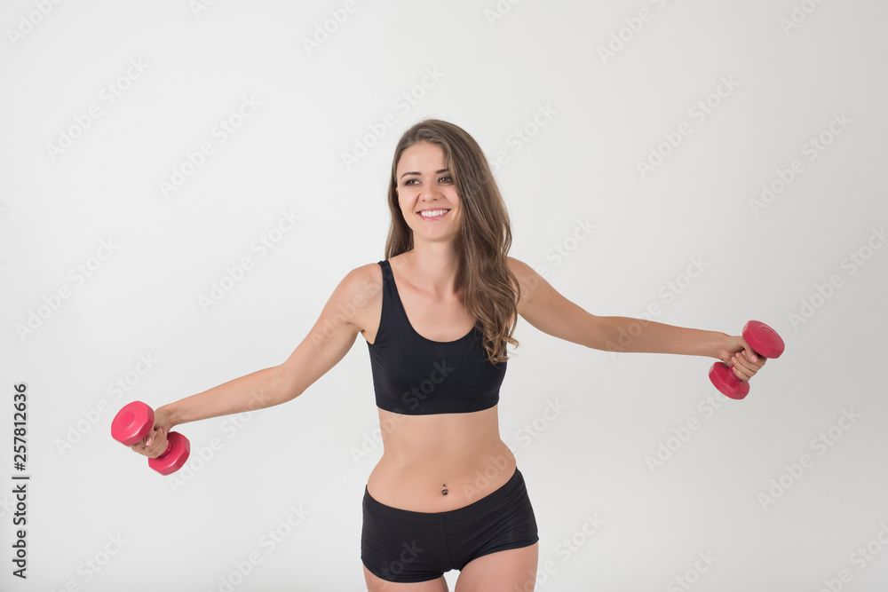 Fototapeta premium Portrait of young beautiful woman making physical exercises with dumbbells