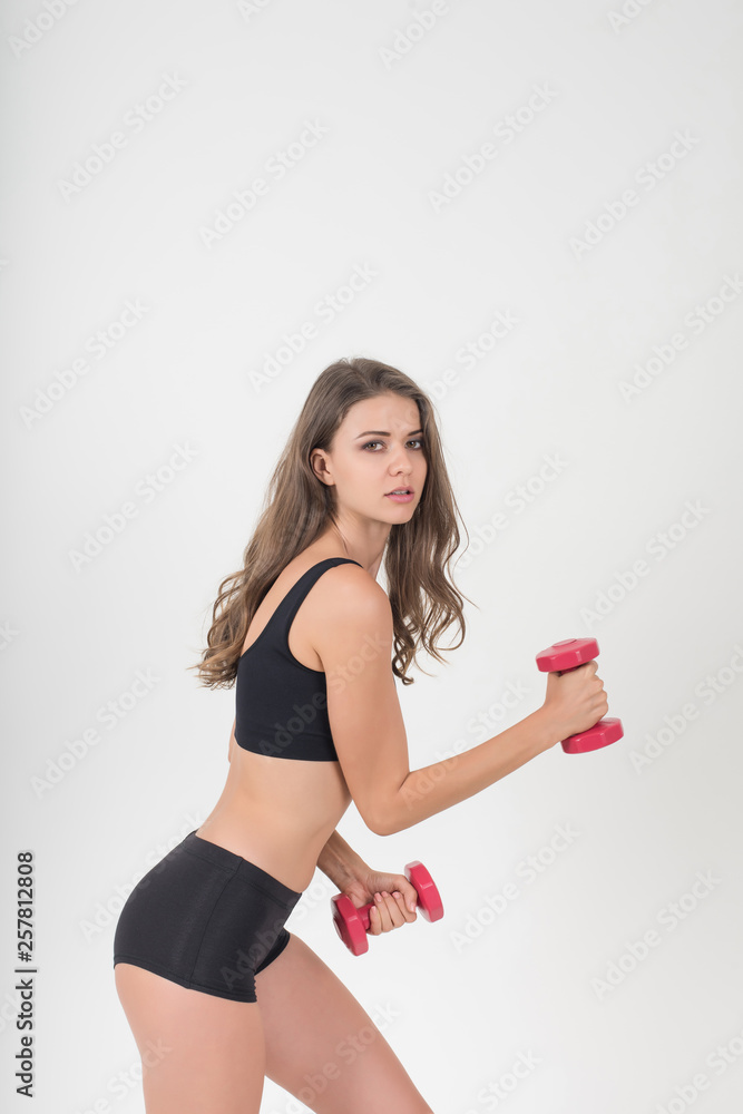 Portrait of young beautiful woman making physical exercises with dumbbells Portrait of young beautiful woman making physical exercises with dumbbells
