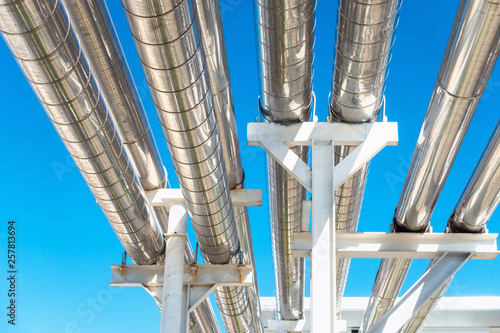 Cooling Chiller or Steam Pipeline and Insulation of Manufacturing in Oil and Gas Industrial, Petrochemical Distribution Pipe at Refinery Plant. Overhead Steel Pipe Support on Blue Sky Background.