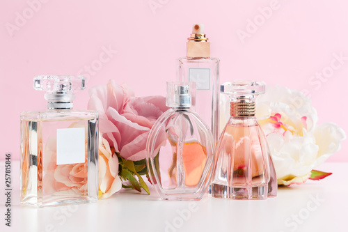 Bottle of perfume with flowers on color background photo