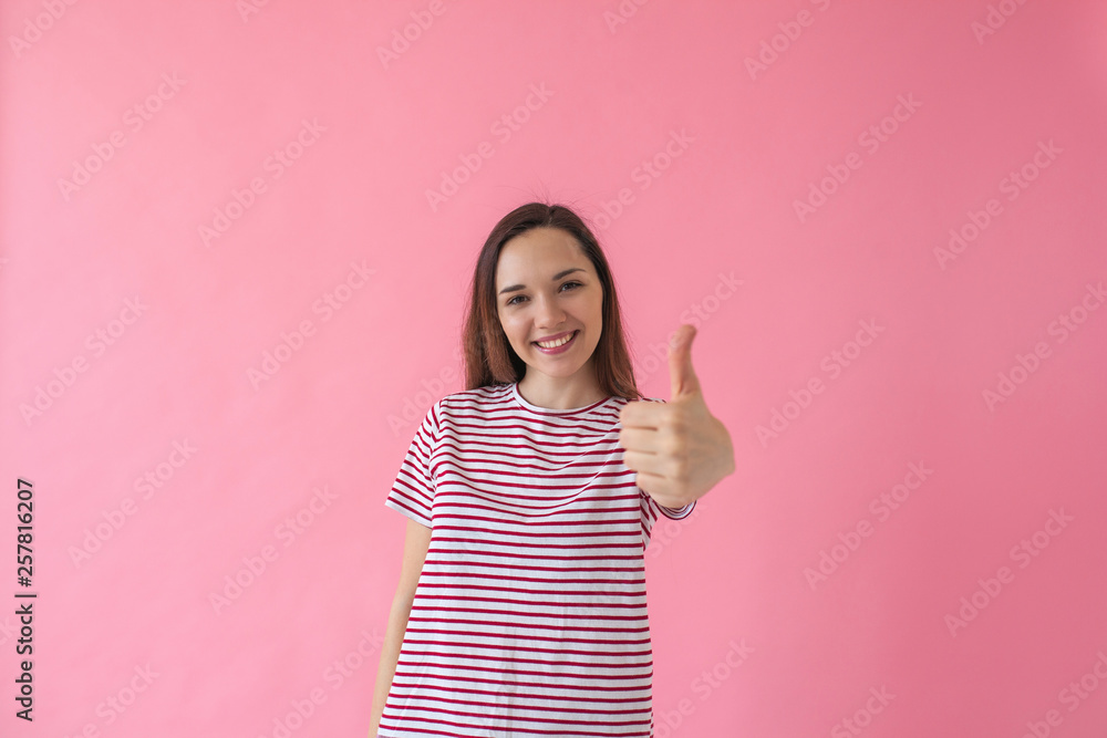 Positive smiling girl on a pink background shows fingers gesture meaning Like or Ok. Positive smiling girl on a pink background shows fingers gesture meaning Like or Ok.