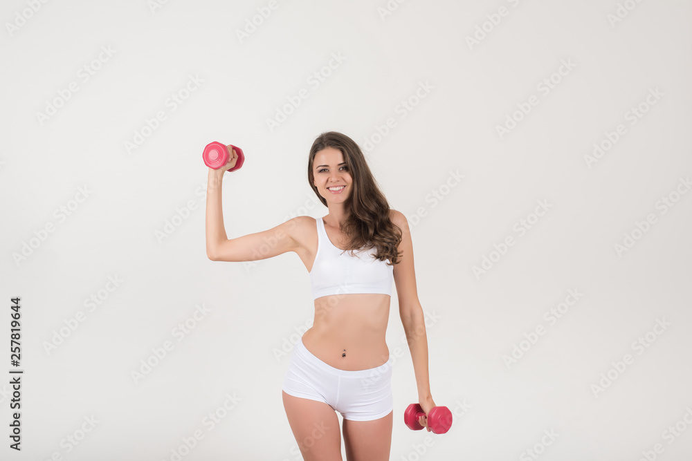 Portrait of young beautiful woman making physical exercises with dumbbells Portrait of young beautiful woman making physical exercises with dumbbells