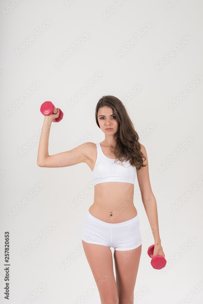 Portrait of young beautiful woman making physical exercises with dumbbells Portrait of young beautiful woman making physical exercises with dumbbells