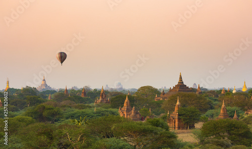 Stunning view of the beautiful Bagan ancient city (formerly Pagan) during sunset with a hot air balloon flying over the temples. The Bagan Archaeological Zone is a main attraction in Myanmar.