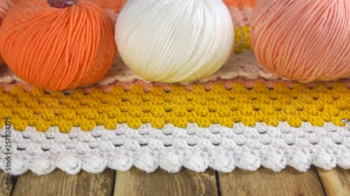 Skeins of color yarn and a crochet hooks on a colorful crocheted bedspread on a wooden background. Close-up
