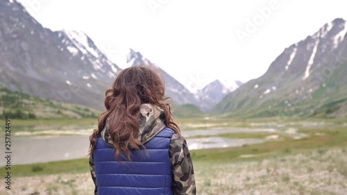 Young woman tourist in a blue vest enjoys nature against the backdrop of mountains. mountain Altai