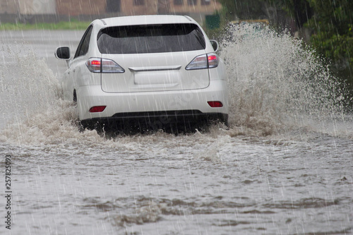 driving car on a wet street with splashing water in flood road at rain day