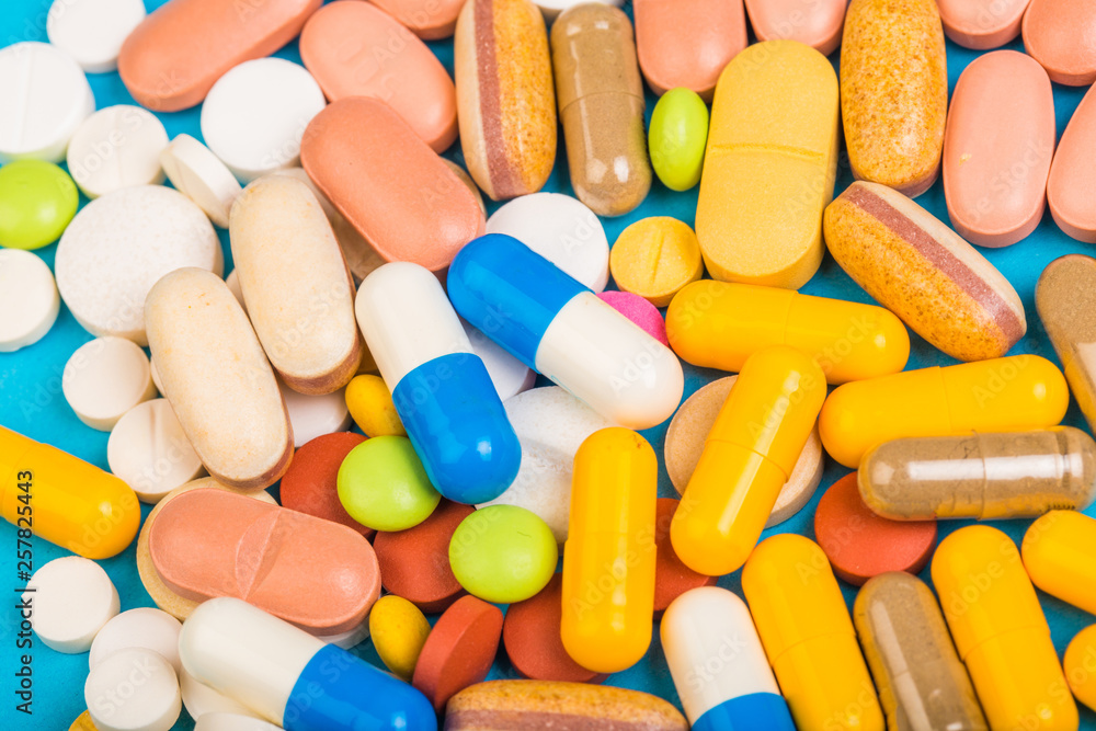 set of multi-colored tablets and capsules on a blue background set of multi-colored tablets and capsules on a blue background