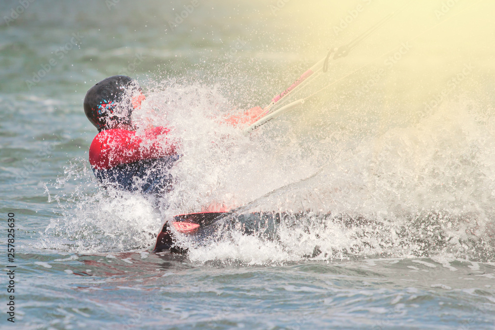 Fototapeta premium Kitesurfing. The young man is flying on the sea wave on the Board at sunny day
