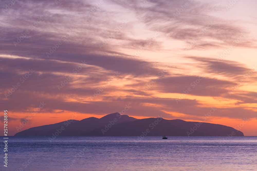 View of Hydra island against colorful morning sky from Spetses, Greece. 