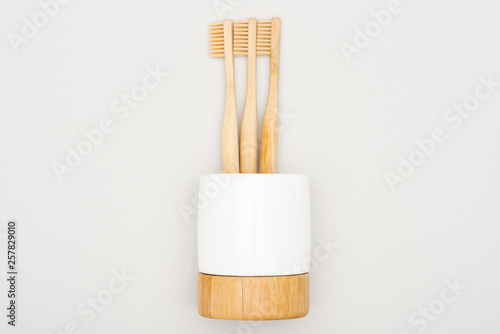 natural bamboo toothbrushes in stand on grey background