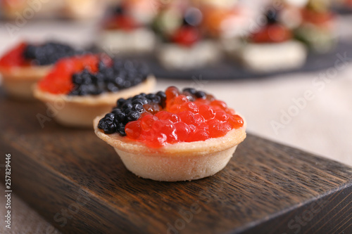 Tartlets with caviar on wooden board, closeup
