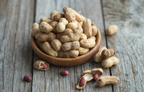 Close up view of shelled peanuts in wooden background.