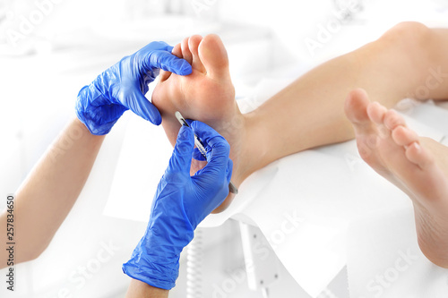 Podiatry. Removing calluses with a scalpel at the beautician. photo