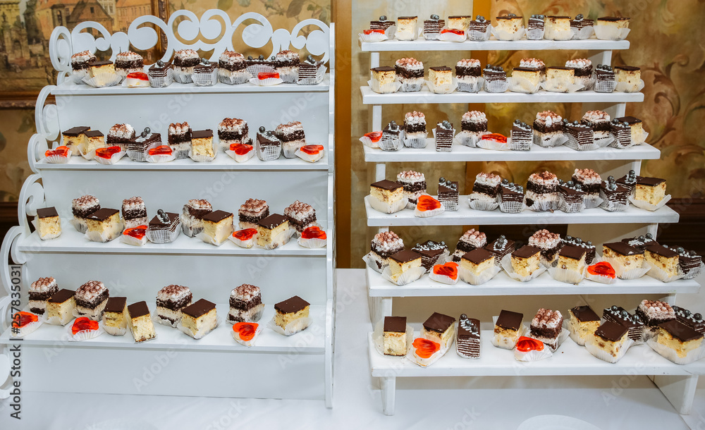 Delicious candy bar at the wedding reception. Chocolate cakes and muffins.Sweet red hearts. Desserts for guests.