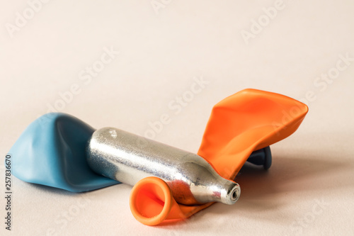 close up metal bulb for laughing gas, party drugs, with balloons.  Against white background.